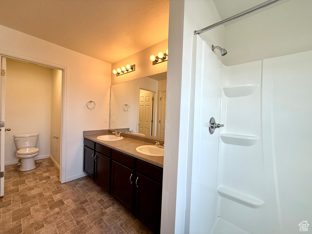 Bathroom with a shower, a sink, toilet, and baseboards