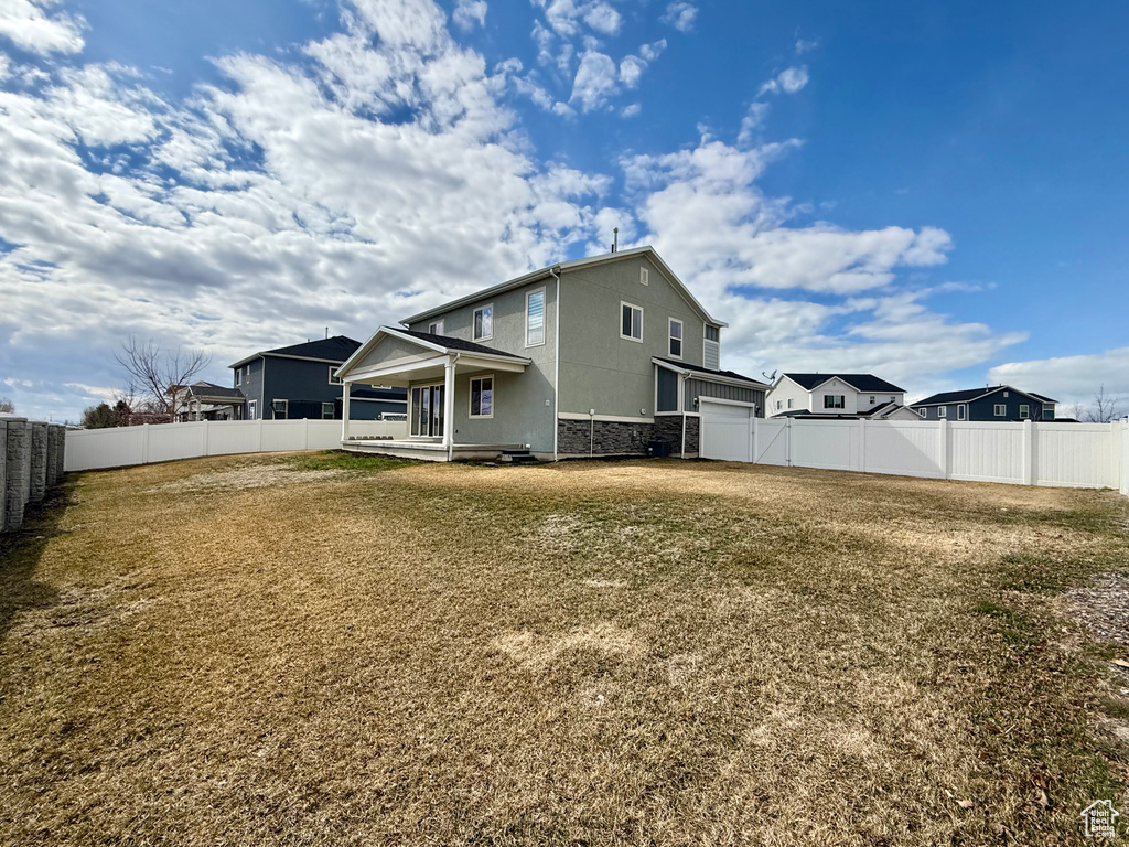 Rear view of property with a fenced backyard and a lawn