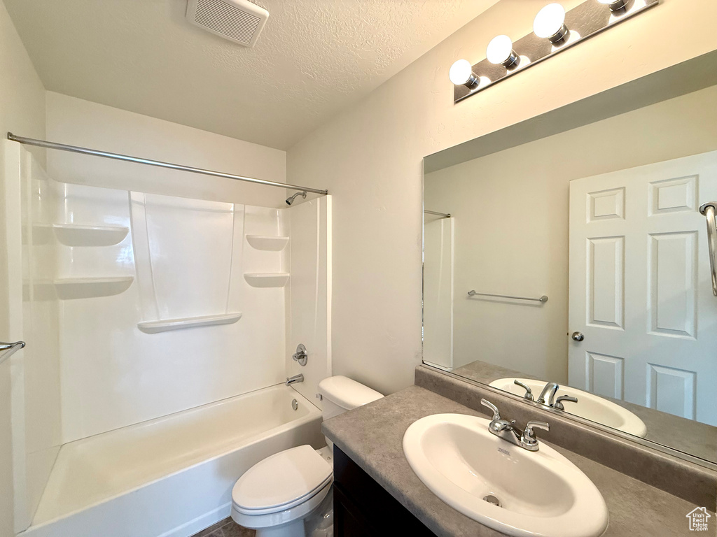 Full bathroom featuring a textured ceiling, toilet, visible vents, vanity, and shower / bathing tub combination