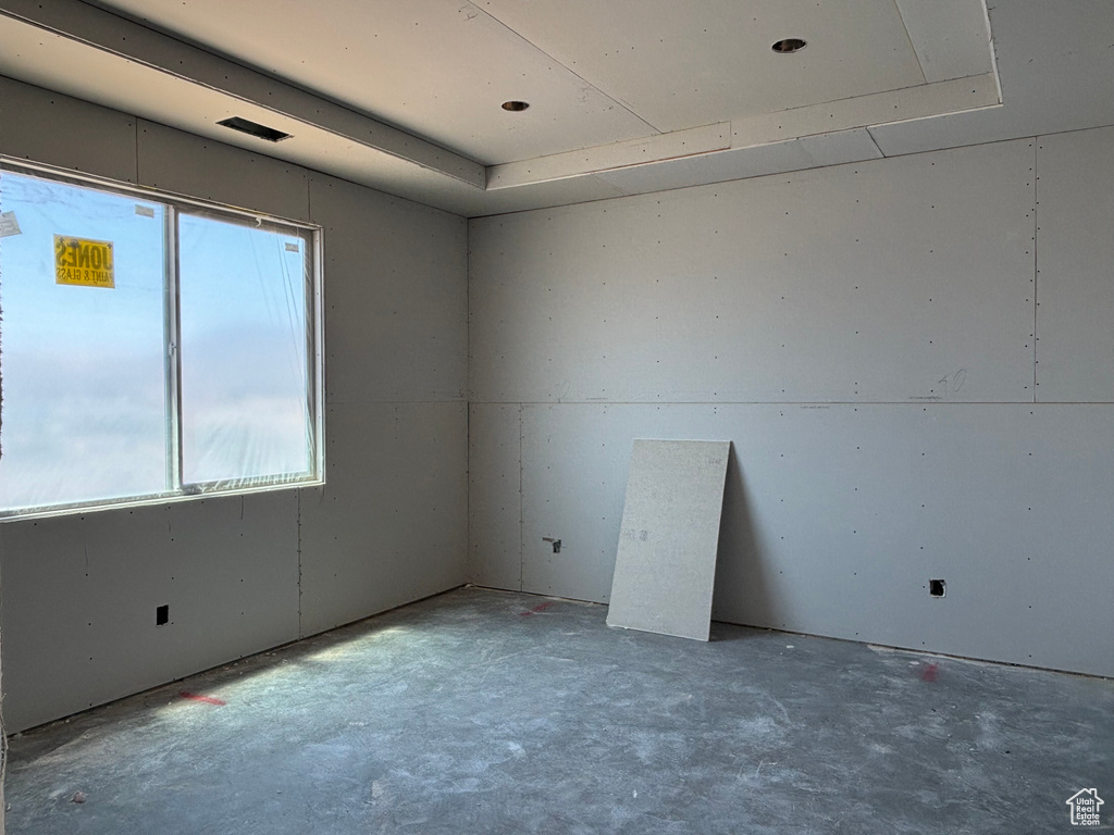 Empty room featuring a raised ceiling and concrete floors