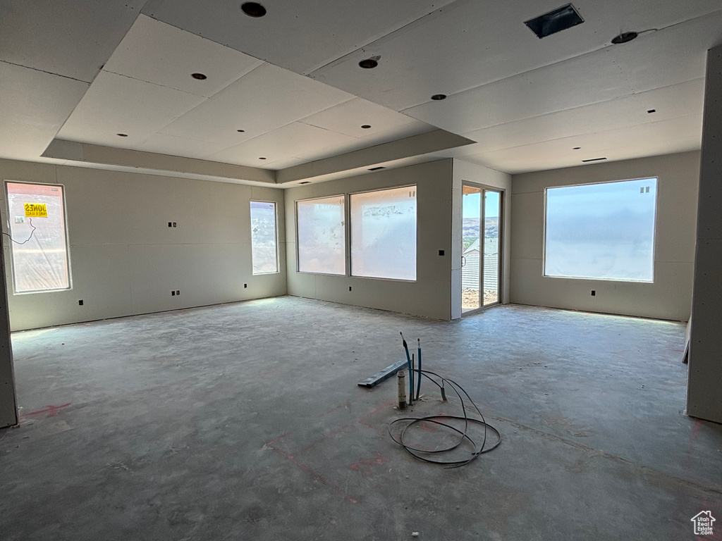 Unfurnished room featuring unfinished concrete flooring and a raised ceiling