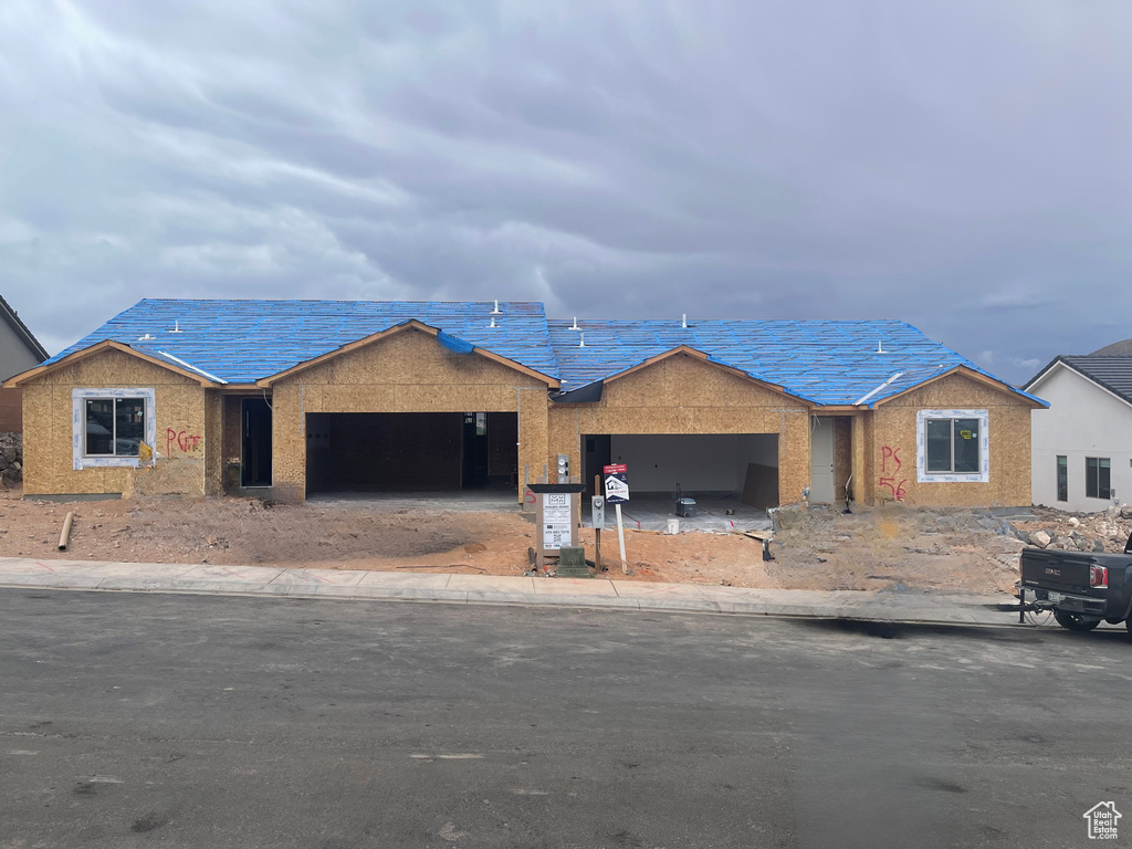 Unfinished property featuring an attached garage, driveway, and stucco siding