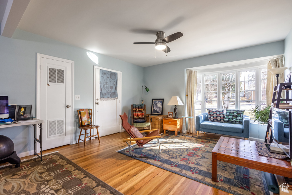 Living room with wood finished floors, a ceiling fan, and an office area