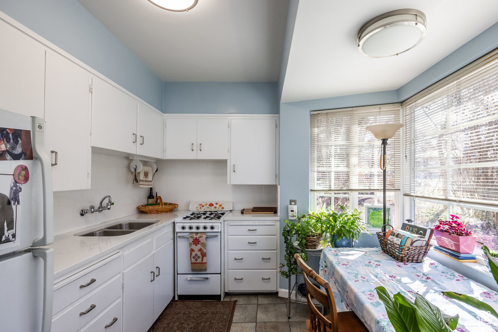 Kitchen featuring white appliances, a sink, light countertops, and white cabinets