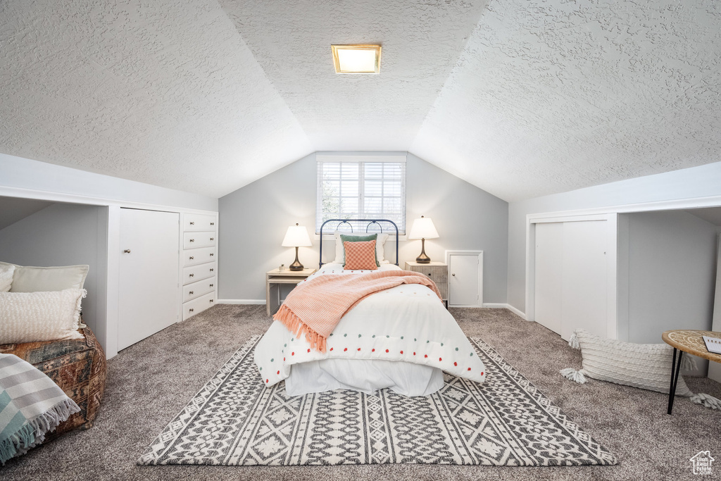 Bedroom with carpet, a textured ceiling, vaulted ceiling, baseboards, and a closet