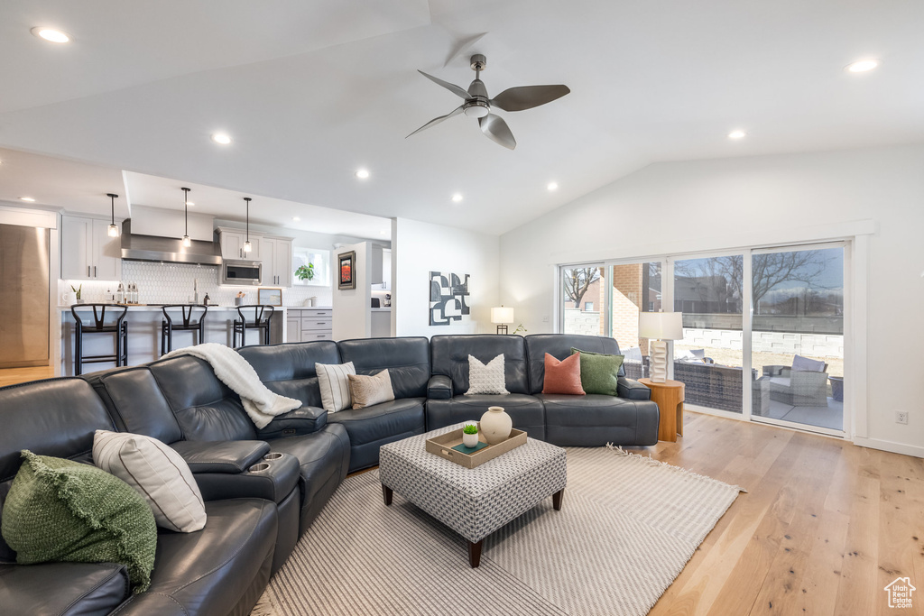 Living room featuring a ceiling fan, lofted ceiling, light wood-style flooring, and recessed lighting