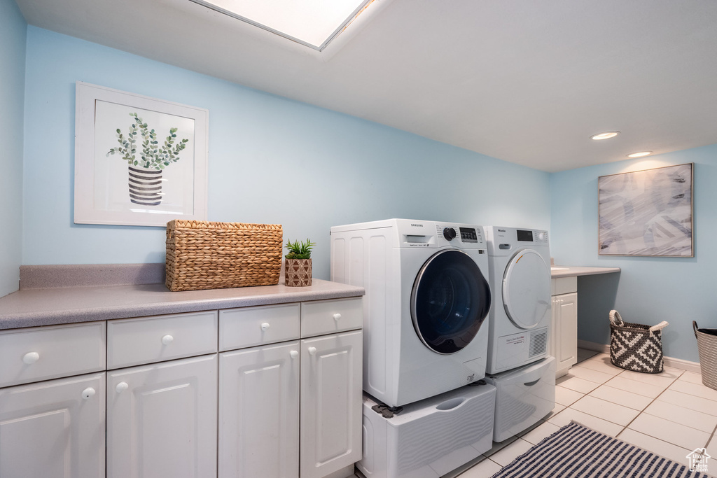 Washroom featuring separate washer and dryer, cabinet space, light tile patterned floors, and recessed lighting