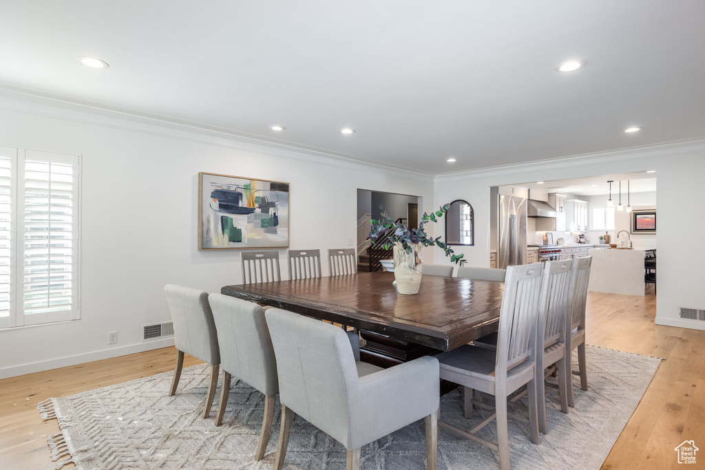 Dining room with crown molding, light wood-type flooring, recessed lighting, and baseboards