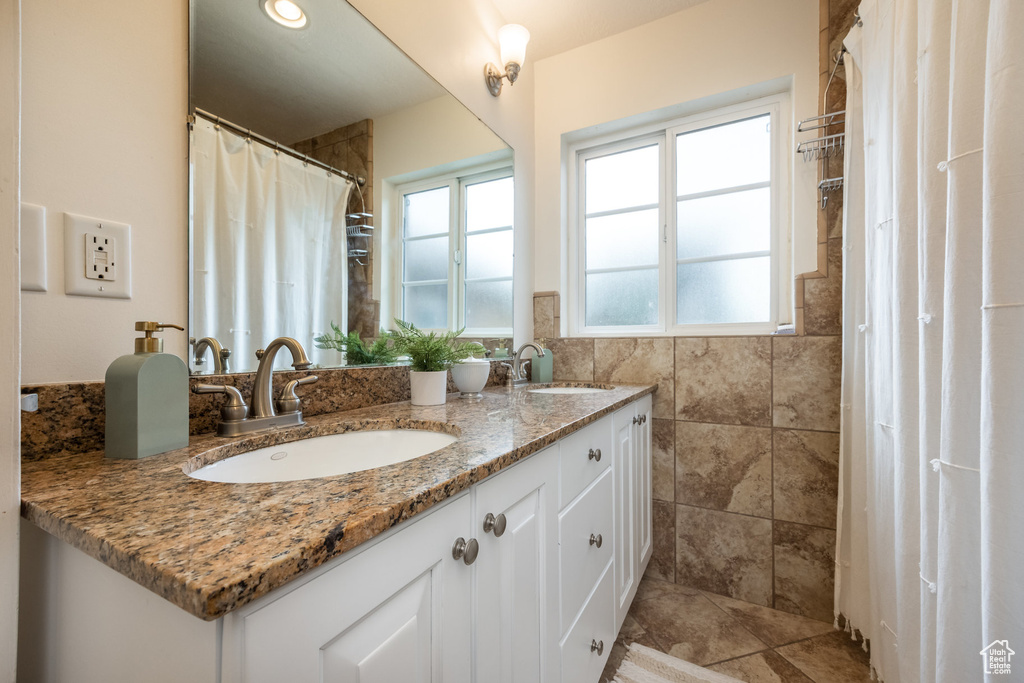 Bathroom with double vanity, tile walls, and a shower with shower curtain