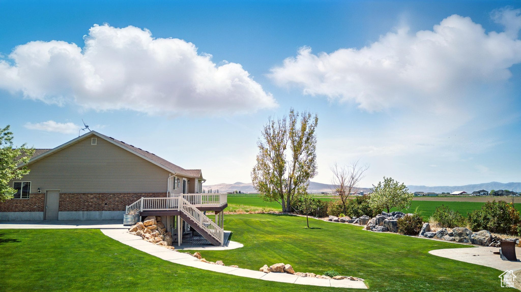 View of yard with stairs and a deck with mountain view