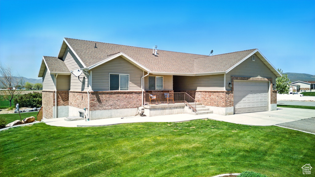 Ranch-style house featuring concrete driveway, a front yard, brick siding, and an attached garage