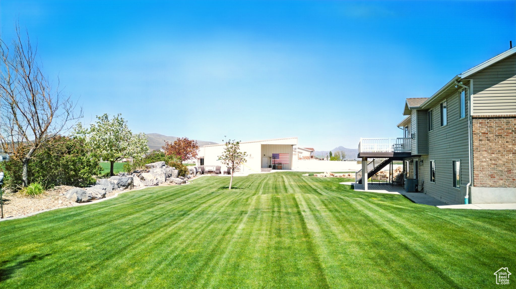 View of yard with a wooden deck and central AC