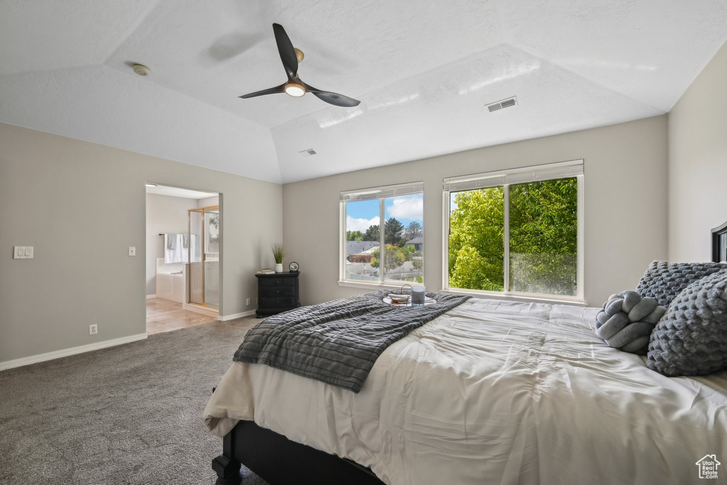 Bedroom with vaulted ceiling, carpet flooring, baseboards, ceiling fan, and ensuite bathroom