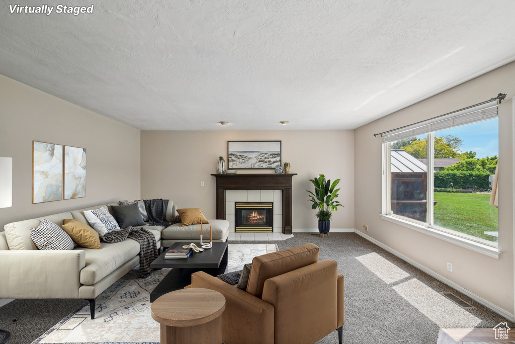 Living area with baseboards, carpet flooring, a tiled fireplace, and a textured ceiling