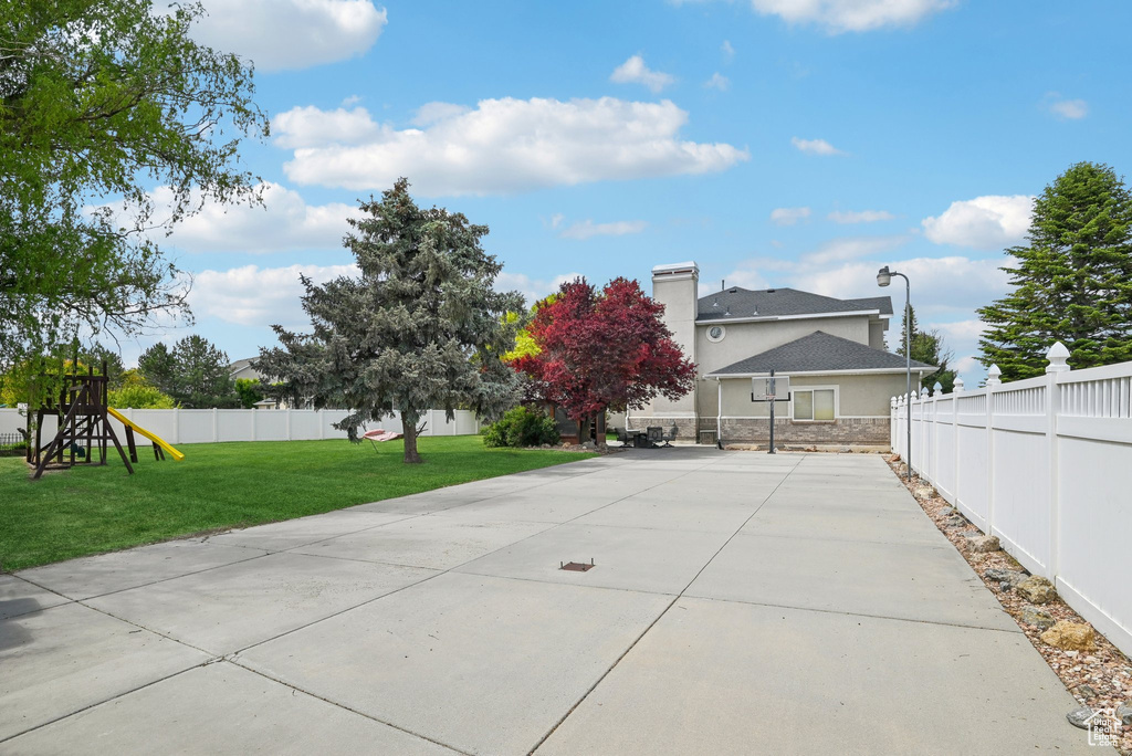Back of house featuring a playground, stucco siding, stone siding, and a chimney