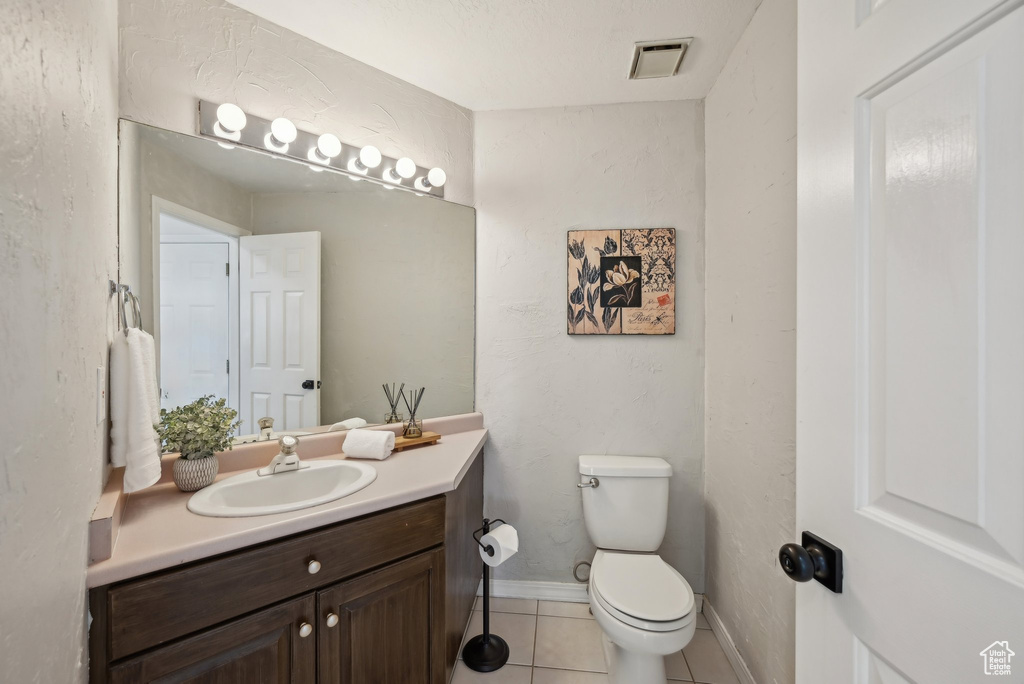Bathroom with toilet, vanity, tile patterned flooring, and baseboards