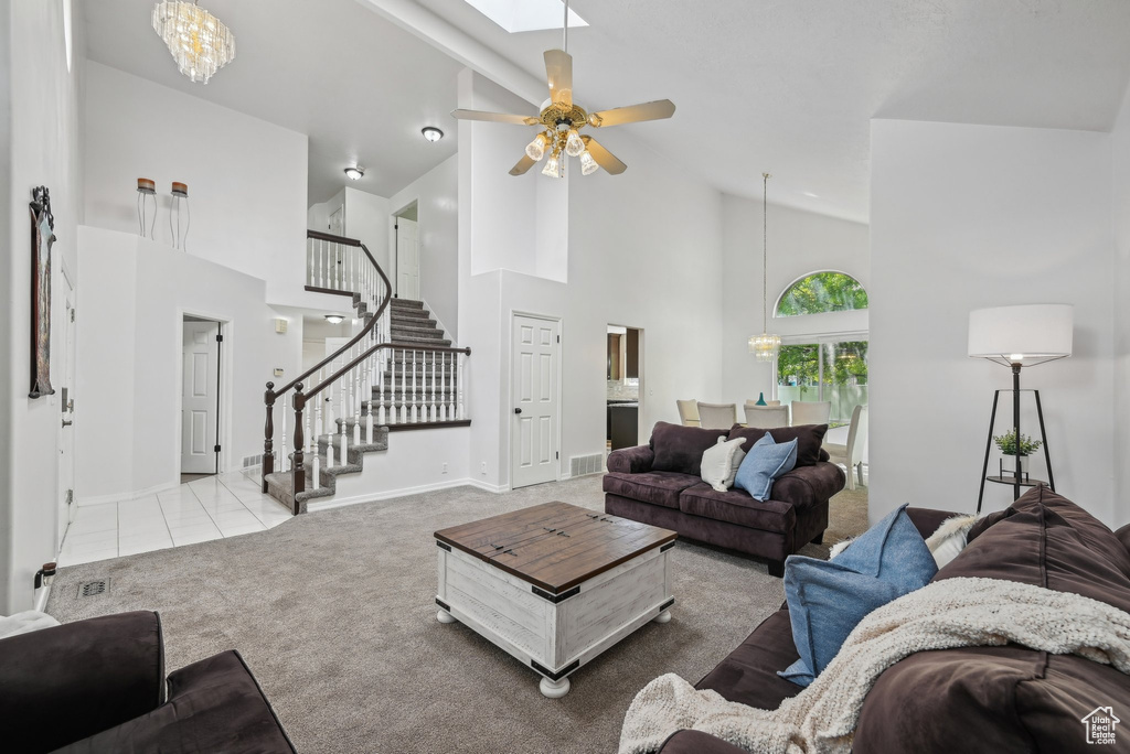 Living room with high vaulted ceiling, stairs, carpet flooring, baseboards, and ceiling fan