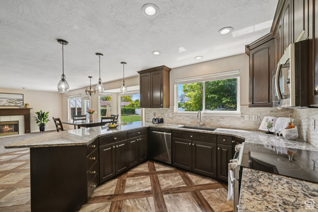 Kitchen with stainless steel appliances, a sink, recessed lighting, decorative backsplash, and a peninsula