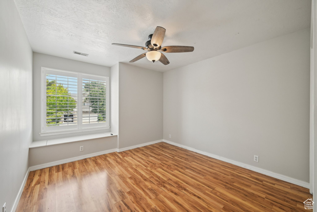 Unfurnished room featuring wood finished floors, ceiling fan, and baseboards