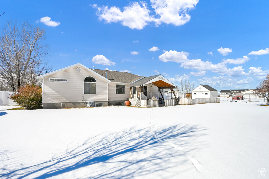 Snow covered rear of property featuring covered porch and fence