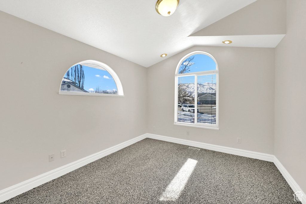 Empty room with carpet floors, lofted ceiling, and baseboards