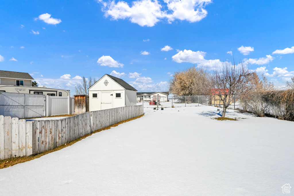 Snowy yard featuring an outdoor structure and a fenced backyard