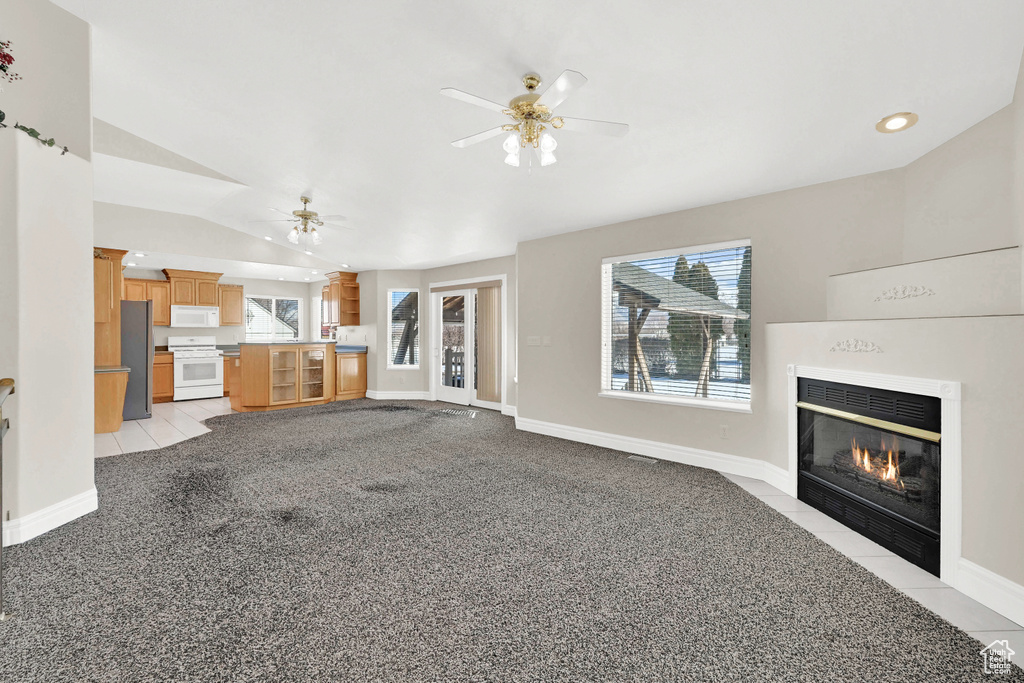 Unfurnished living room featuring a wealth of natural light, a fireplace with flush hearth, baseboards, and a ceiling fan