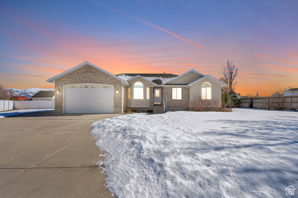 Single story home with driveway, an attached garage, fence, and brick siding