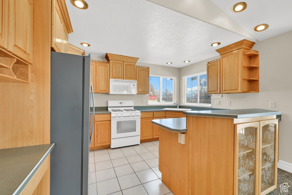 Kitchen with white appliances, light tile patterned floors, a peninsula, open shelves, and a sink