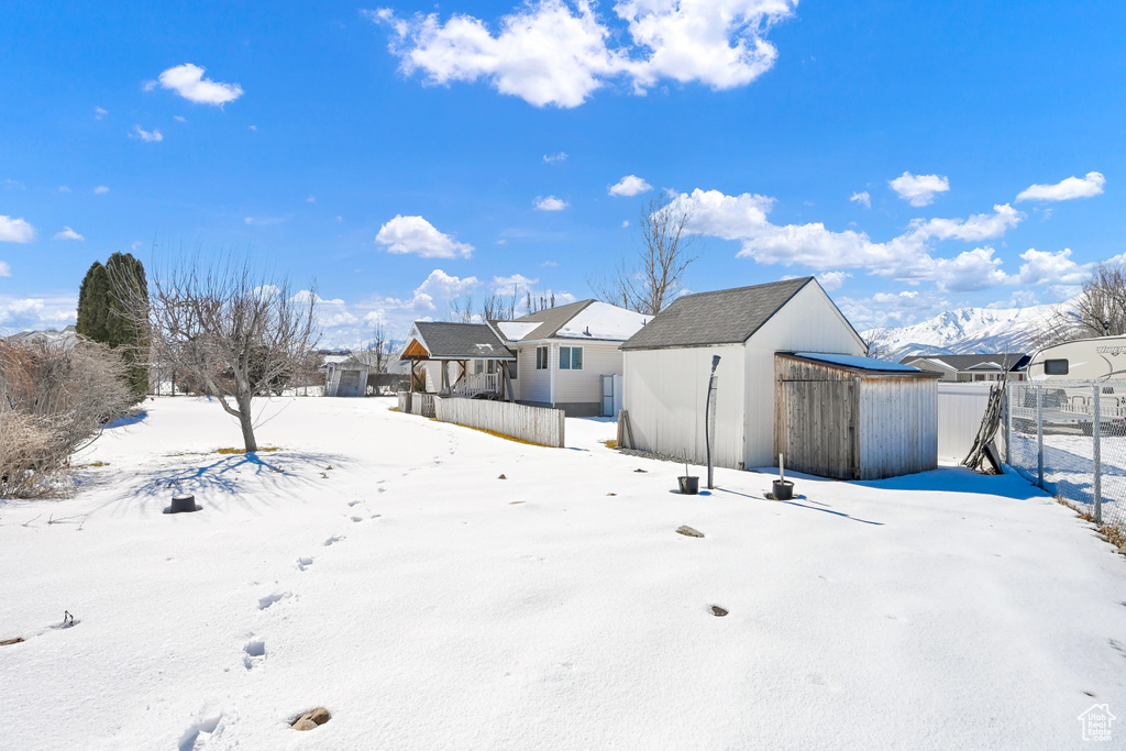 Yard covered in snow with an outbuilding, fence, and a storage unit