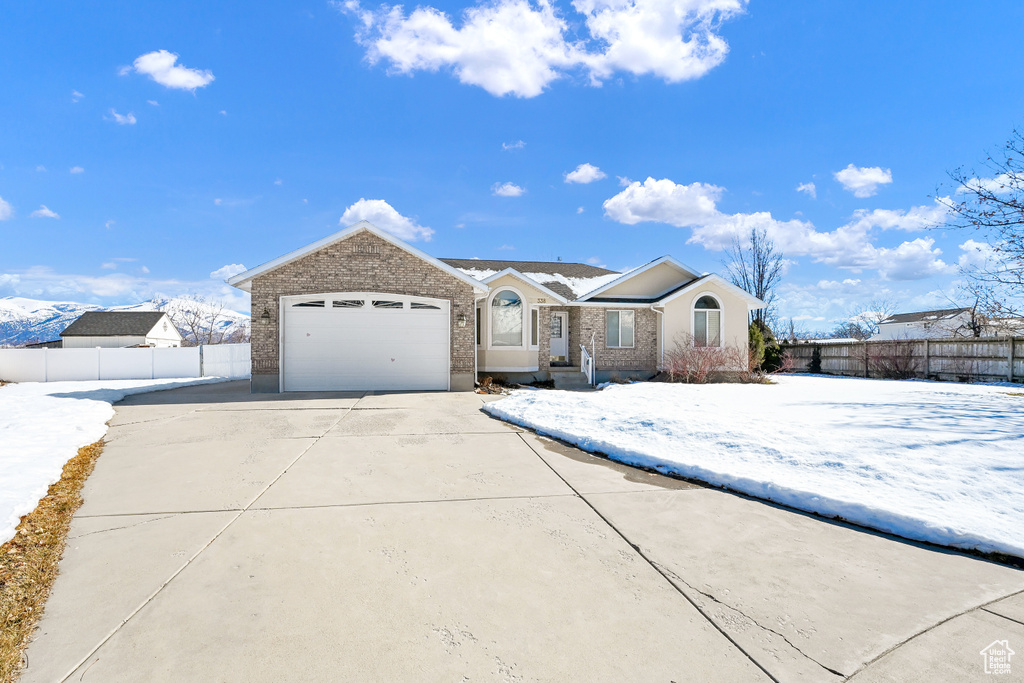 Single story home featuring driveway, fence, and brick siding
