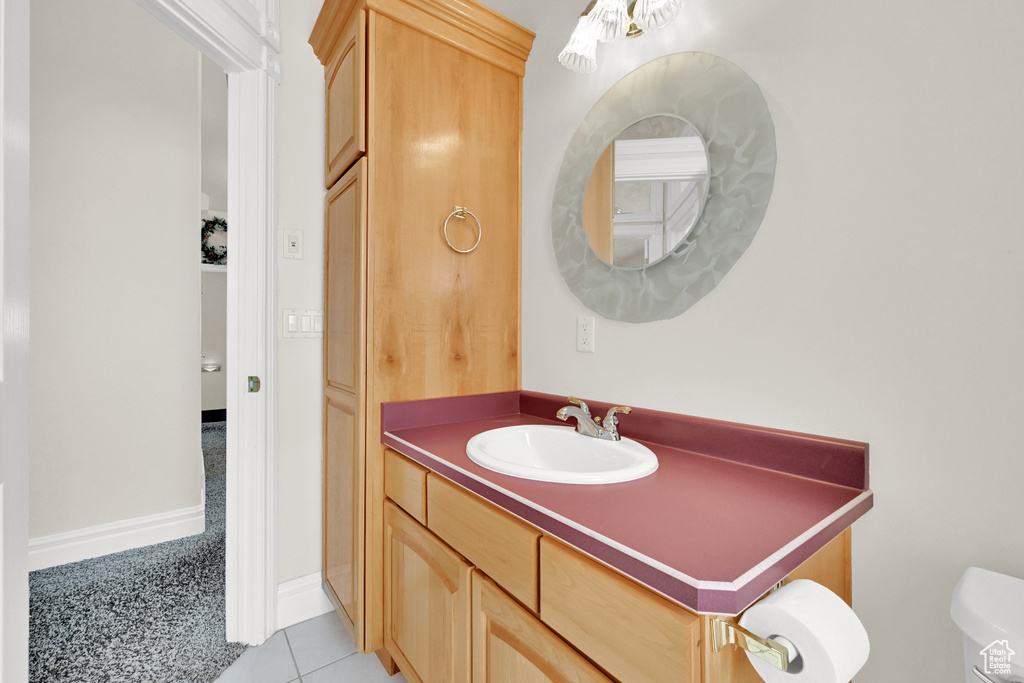 Half bath with toilet, vanity, and tile patterned floors
