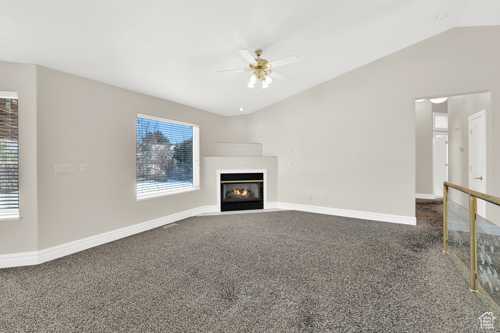 Unfurnished living room with carpet, vaulted ceiling, and a wealth of natural light