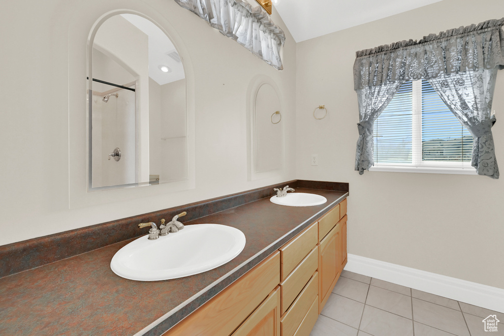 Full bathroom with double vanity, tile patterned flooring, a sink, and baseboards