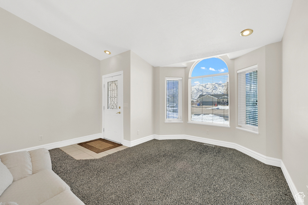 Unfurnished living room featuring lofted ceiling, baseboards, dark carpet, and recessed lighting