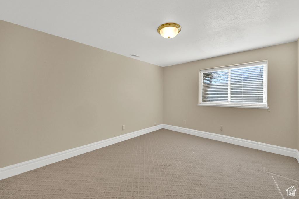 Spare room featuring carpet, visible vents, and baseboards