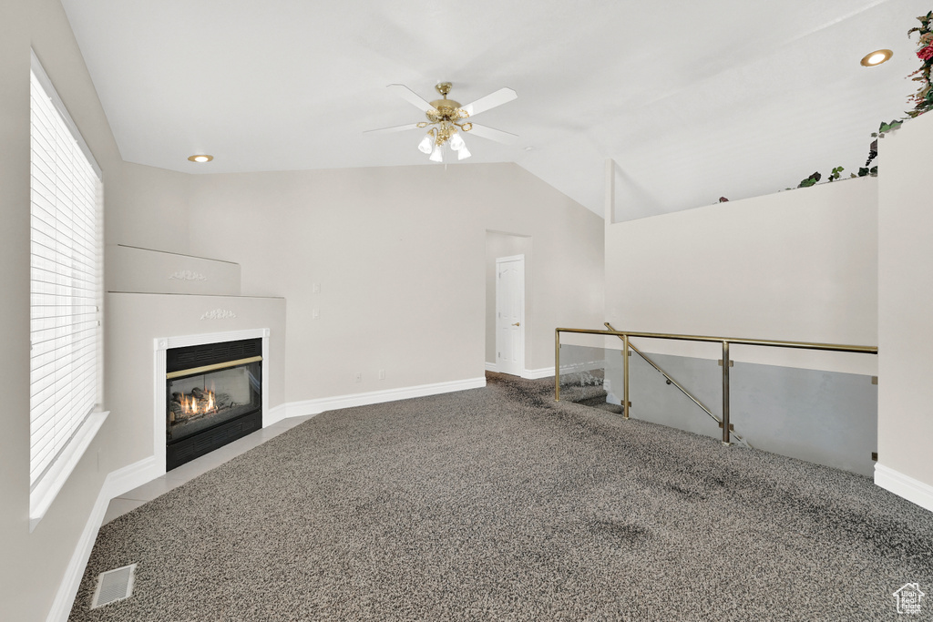 Unfurnished living room with carpet floors, a healthy amount of sunlight, a fireplace with flush hearth, and visible vents