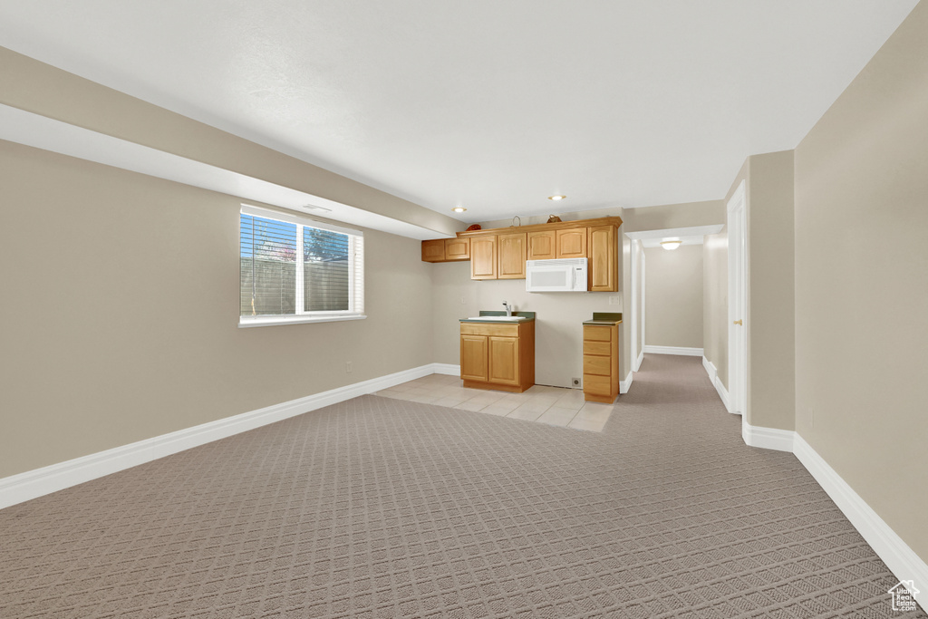 Kitchen with baseboards, light colored carpet, white microwave, open floor plan, and recessed lighting