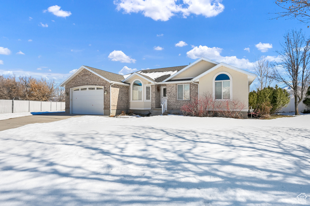 Ranch-style house with brick siding, fence, driveway, and an attached garage