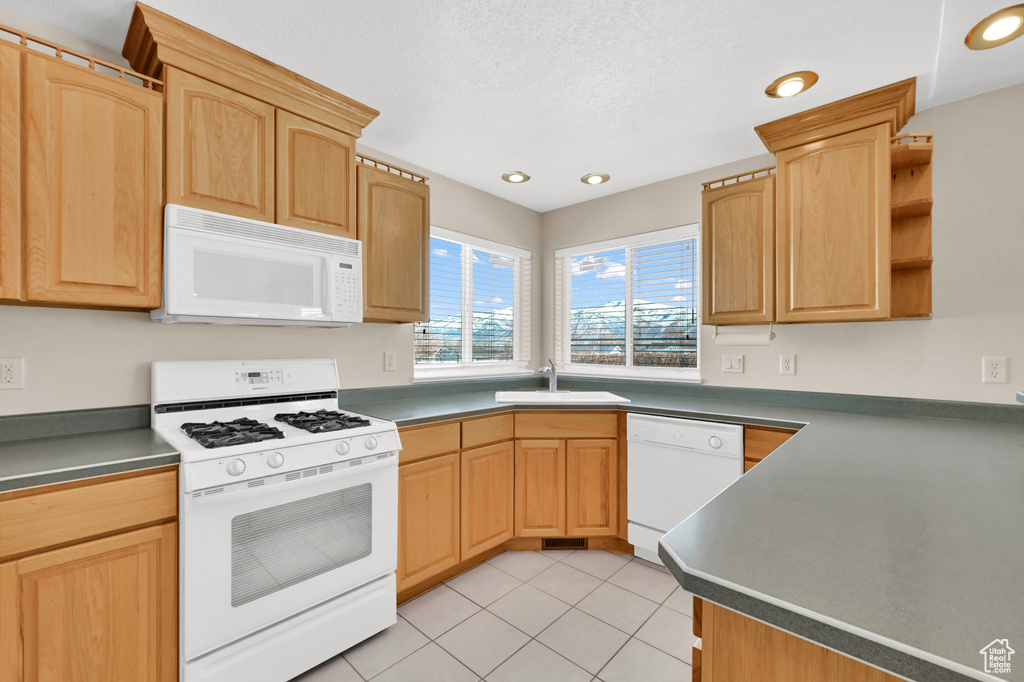 Kitchen with white appliances, light brown cabinets, a sink, and light tile patterned floors