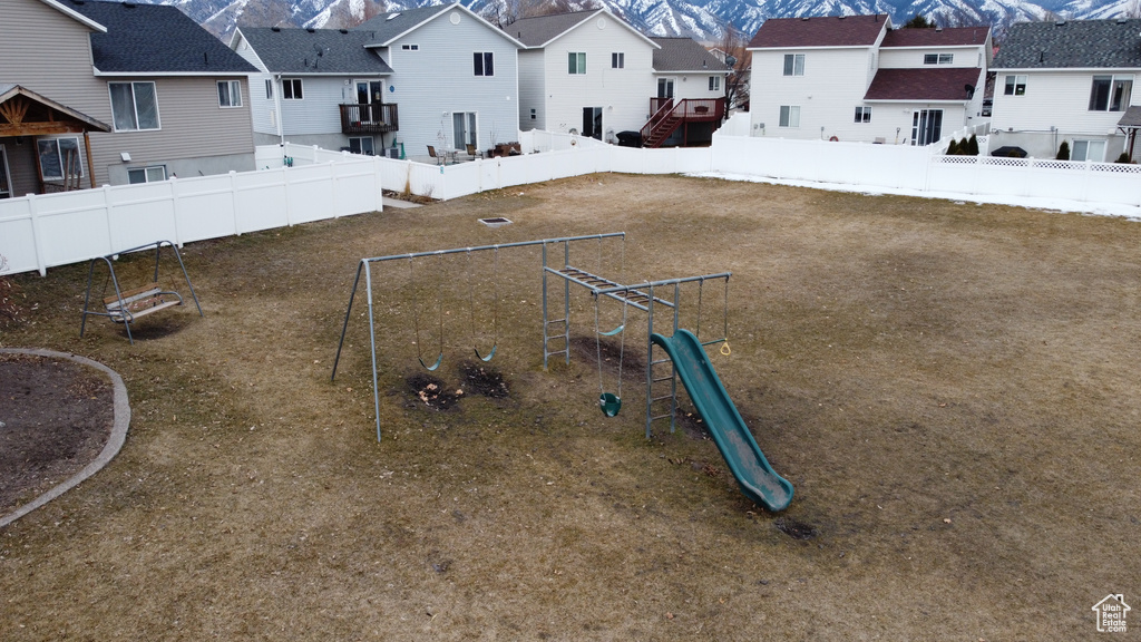 View of yard featuring a fenced backyard, a residential view, a mountain view, and a playground