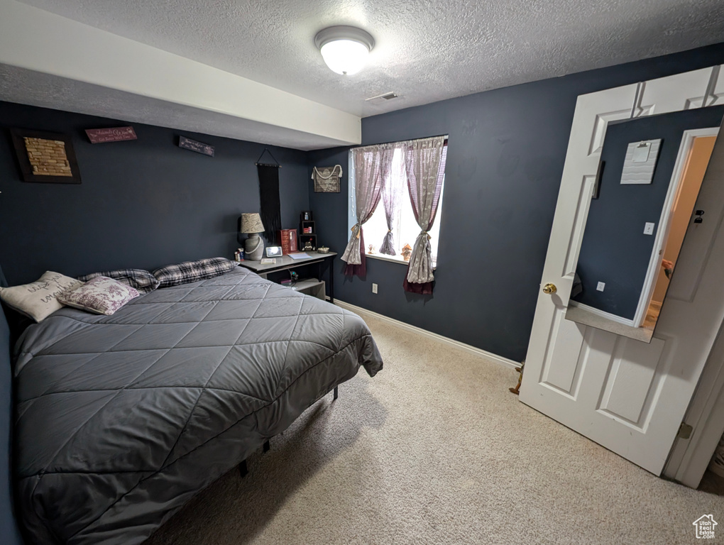 Bedroom with a textured ceiling, carpet floors, visible vents, and baseboards