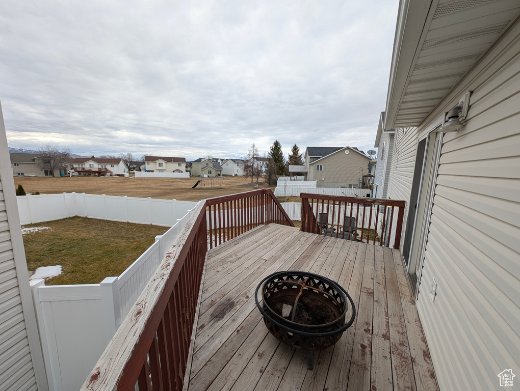 Wooden terrace featuring a residential view, a fenced backyard, and a lawn