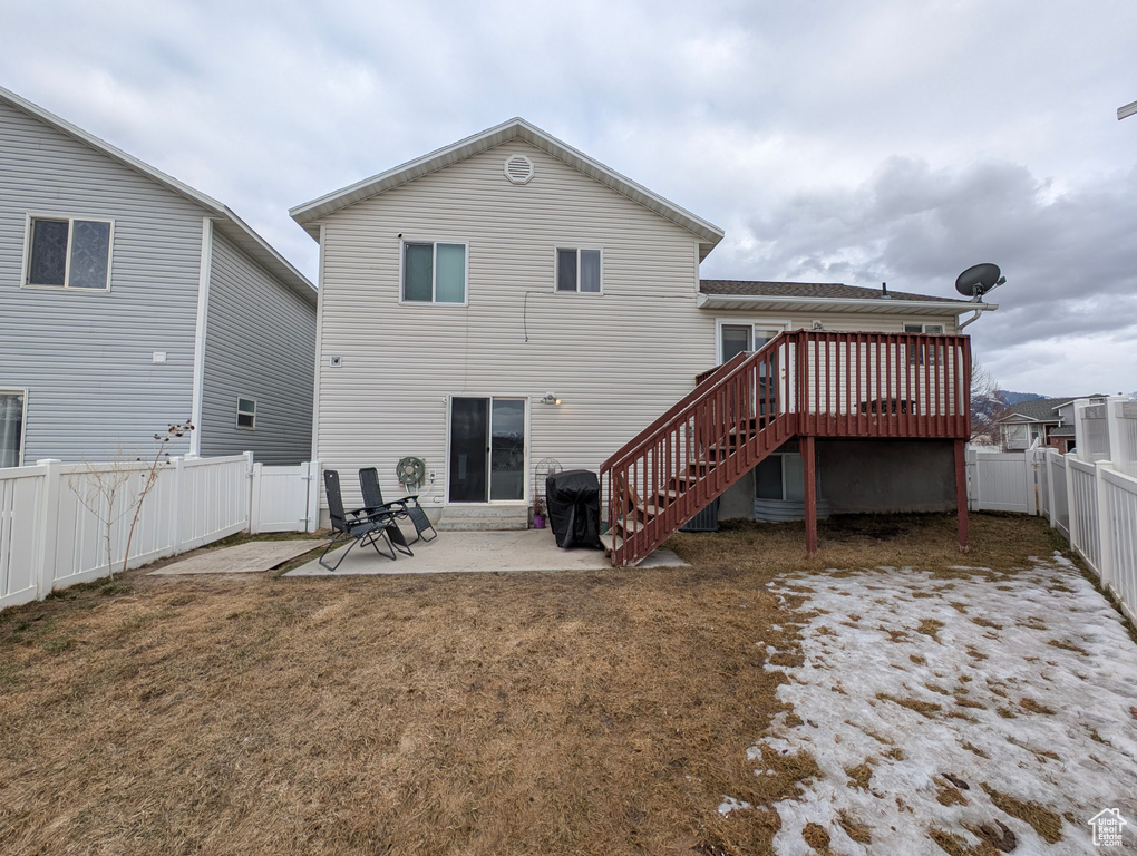 Rear view of property featuring a patio, a fenced backyard, stairway, a lawn, and a wooden deck