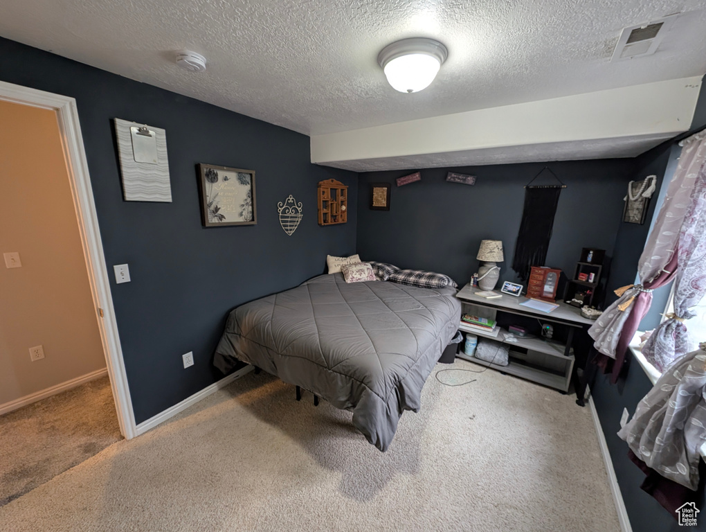 Bedroom featuring a textured ceiling, carpet, visible vents, and baseboards