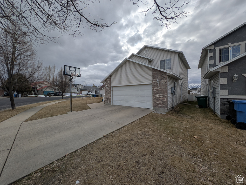 View of side of property featuring a garage, brick siding, and driveway
