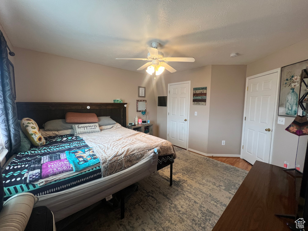 Bedroom featuring a textured ceiling, wood finished floors, a ceiling fan, and baseboards