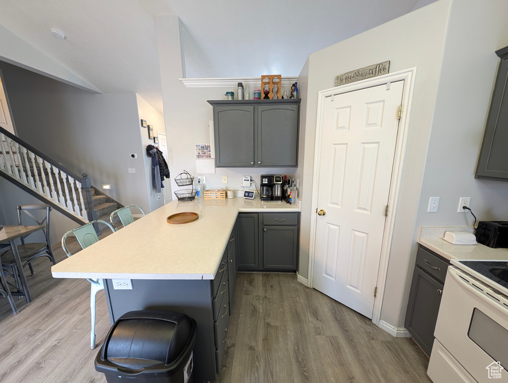 Kitchen with light countertops, a peninsula, a kitchen breakfast bar, and wood finished floors