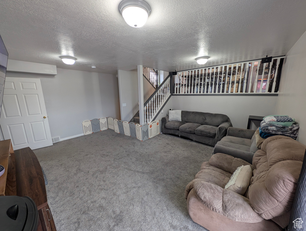 Carpeted living room with stairway and a textured ceiling