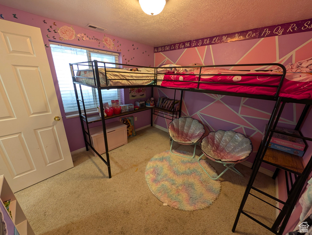 Carpeted bedroom with baseboards, visible vents, and a textured ceiling
